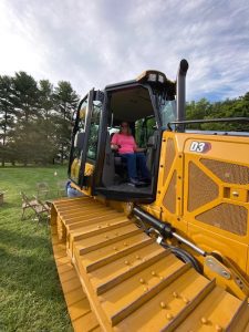 Woman poses on a heavy machinery display by Comer Construction at the National Night Out in Harford County