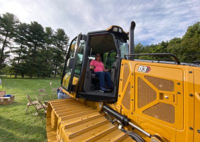 Woman poses on a heavy machinery display by Comer Construction at the National Night Out in Harford County