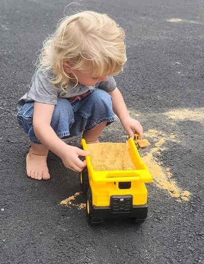 Child playing with a toy dump truck and payloader