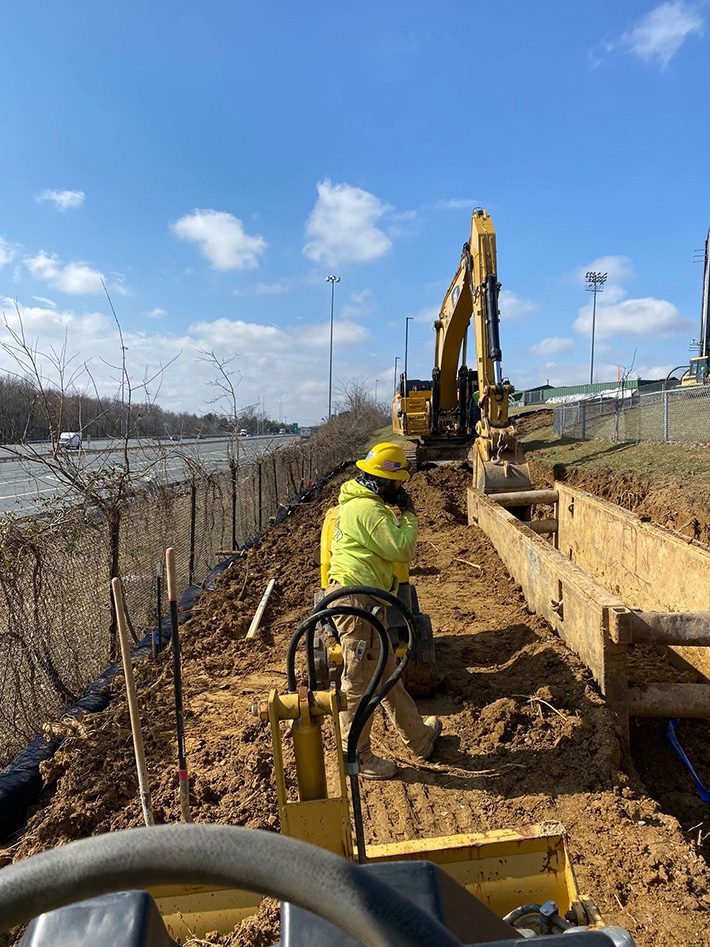 Crew member standing near trench for new waterline extension in Aberdeen, Maryland