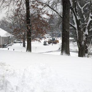 Rubber tire loader clearing snow on a commercial driveway