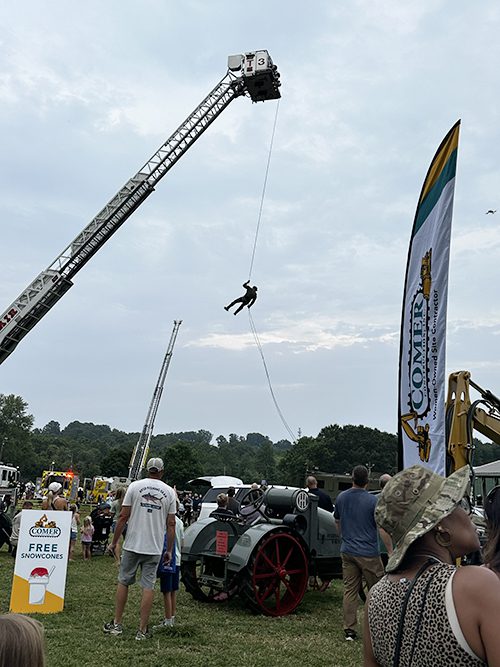 Person rappelling down in front of Comer's display at National Night Out