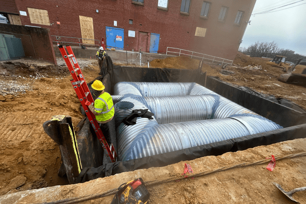 Crews finishing the installation of large corrugated metal detention pipes