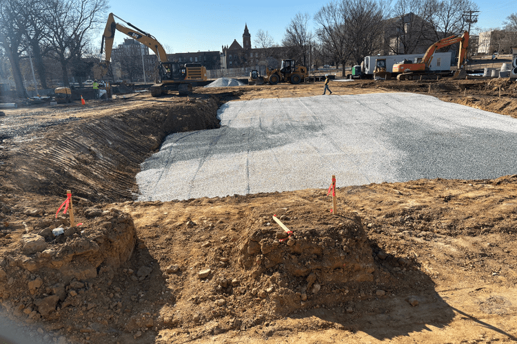 CAT excavator and Hitachi working the site, large gravel bed being prepared, open site with equipment staged across the full 3.5 acres