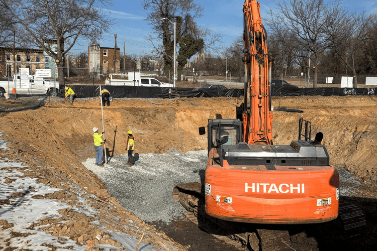 Excavator preparing the site and spreading gravel