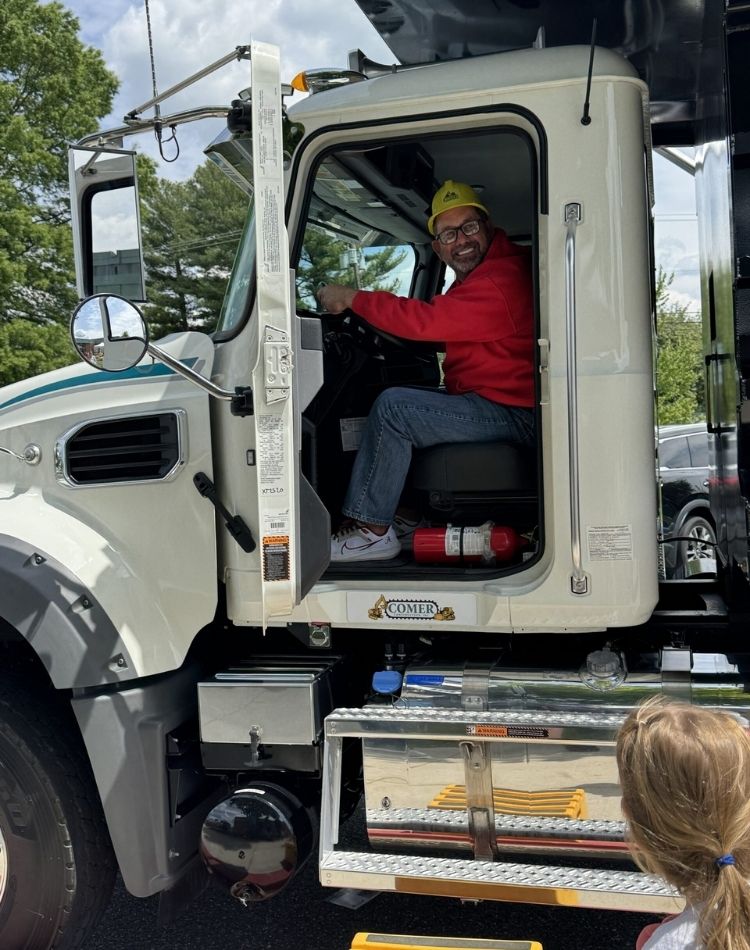Driver smiling from the cab of a dump truck.