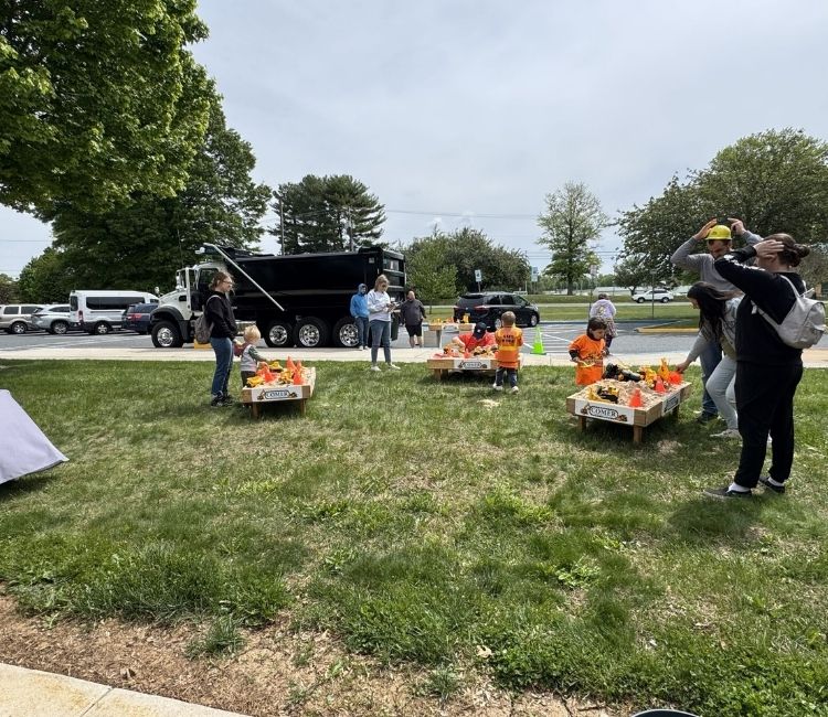 People visiting activity stations near a parked construction truck.
