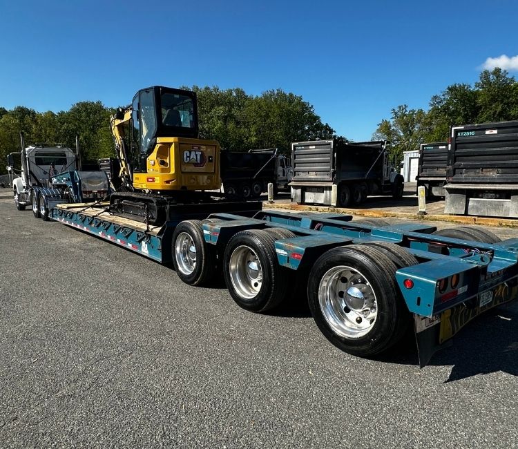 A Comer Construction trailer carrying a yellow excavator.