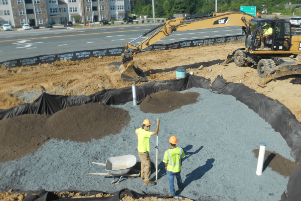 Crews installing a stormwater management system near a busy road