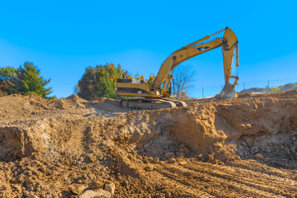 Excavator at a construction site moving dirt on a hill
